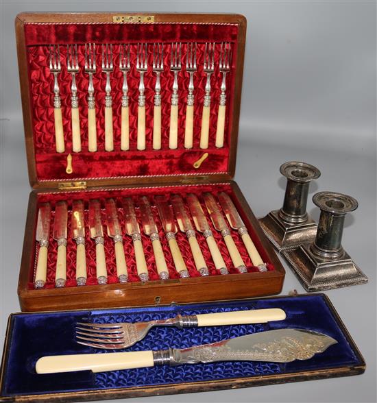 A cased pair of late Victorian ivory handled silver fish servers, pair of dwarf candlesticks and cased plated dessert eaters.